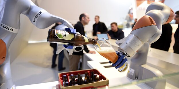 Zwei Roboter in Form von Armen gießen Bier in ein Glas Zwei Roboter in Form von Armen gießen Bier in ein Glas