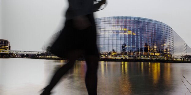 Die Silhouette einer Frau, die vor einem Bild des Europaparlaments vorbeiläuft Die Silhouette einer Frau, die vor einem Bild des Europaparlaments vorbeiläuft