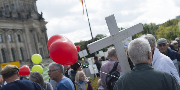 Menschen mit Luftballons. Einer trägt ein weißes Kreuz Menschen mit Luftballons. Einer trägt ein weißes Kreuz