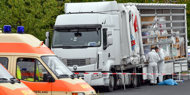 Zwei Rettungswagen und ein Laster. Vor dem Laster stehen zwei Männer.