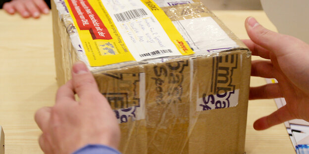 Eine Person greift nach einem Paket. Eine Person greift nach einem Paket.