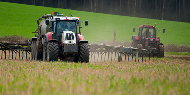 Ein Traktor verteilt Gülle über einem Acker Ein Traktor verteilt Gülle über einem Acker