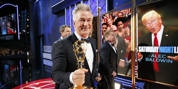 Ein Mann auf einer Bühne mit einer Statuette in der Hand Ein Mann auf einer Bühne mit einer Statuette in der Hand