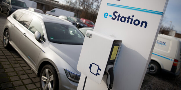Ein Elektroauto vor einer Aufladestation auf einem Parkplatz Ein Elektroauto vor einer Aufladestation auf einem Parkplatz