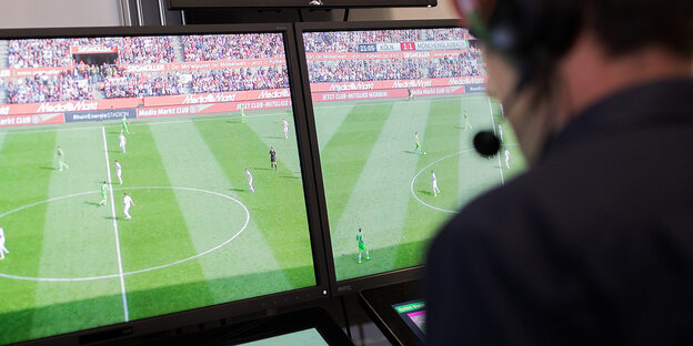 Ein Schiedsrichter guckt auf einen Moniktor mit Fußballübertragung Ein Schiedsrichter guckt auf einen Moniktor mit Fußballübertragung