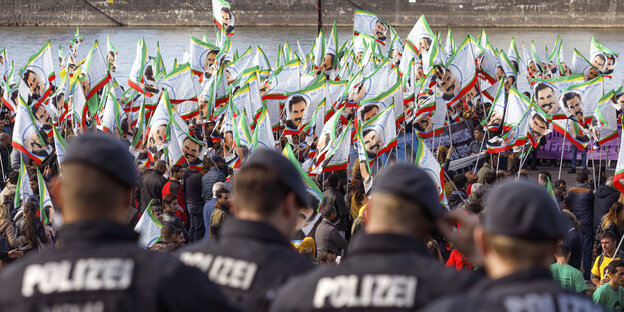 Polizisten stehen vor einer Gruppe Menschen, die Fahnen mit dem Gesicht Öcalans schwenken Polizisten stehen vor einer Gruppe Menschen, die Fahnen mit dem Gesicht Öcalans schwenken