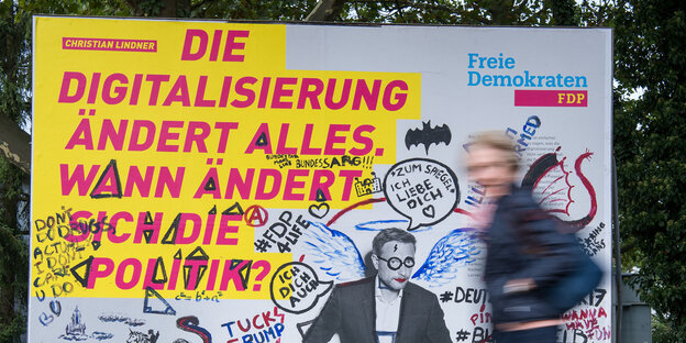 Ein Mensch joggt an einem FDP-Plakat vorbei Ein Mensch joggt an einem FDP-Plakat vorbei