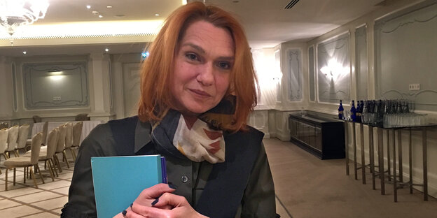 Frau steht in einem festlichen Raum und hält ein Buch in der Hand Frau steht in einem festlichen Raum und hält ein Buch in der Hand