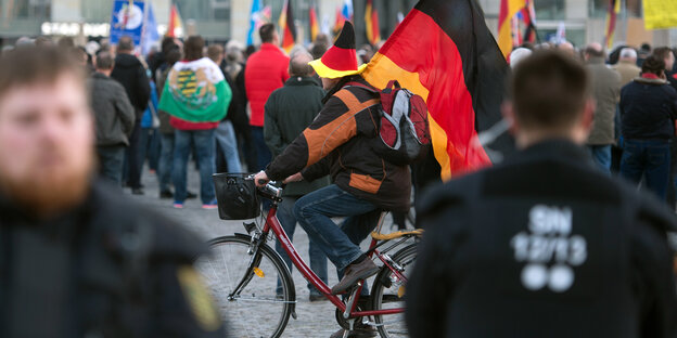 Ein Mann mit Deutschlandfahne fährt durch eine Menschenmenge Ein Mann mit Deutschlandfahne fährt durch eine Menschenmenge