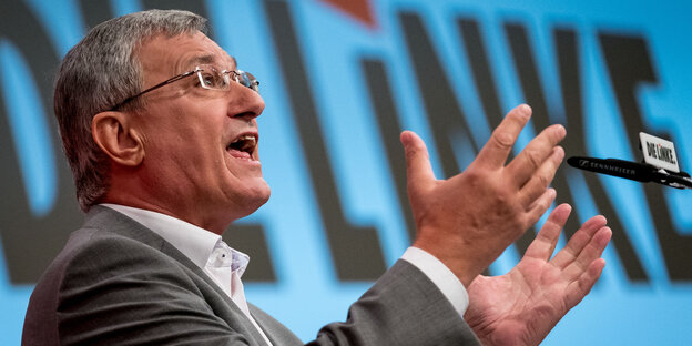 Mann mit Brille hebt die Arme, es ist der Parteichef der Linken, Bernd Riexinger Mann mit Brille hebt die Arme, es ist der Parteichef der Linken, Bernd Riexinger