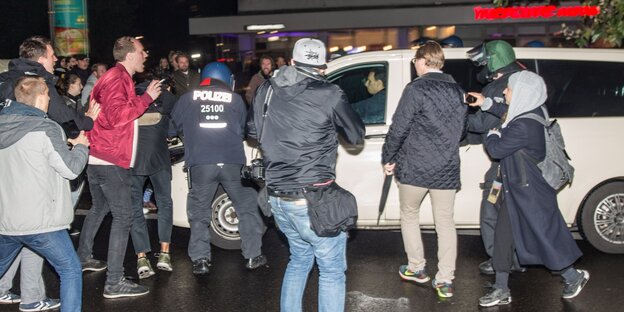 Menschen stehen auf einer Straße um ein Taxi herum Menschen stehen auf einer Straße um ein Taxi herum