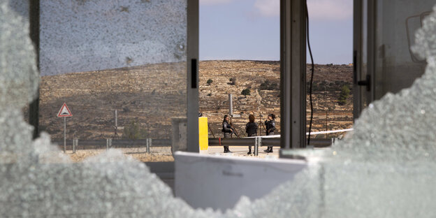Eine zersplitterte Glasscheibe, dahinter ist der Checkpoint und Soldaten zu sehen Eine zersplitterte Glasscheibe, dahinter ist der Checkpoint und Soldaten zu sehen