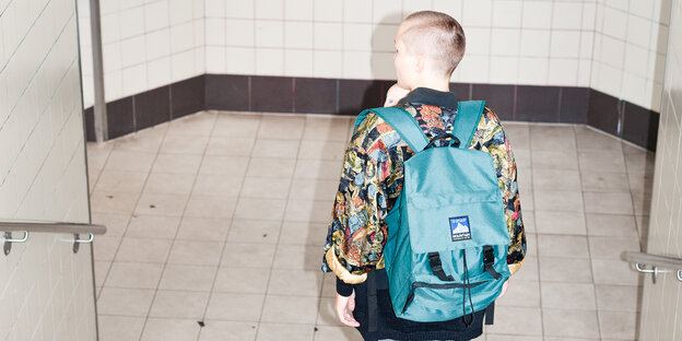 Eine Person mit einem Rucksack geht eine Treppe runter, vor ihrer Brust erkennt man ein Baby Eine Person mit einem Rucksack geht eine Treppe runter, vor ihrer Brust erkennt man ein Baby