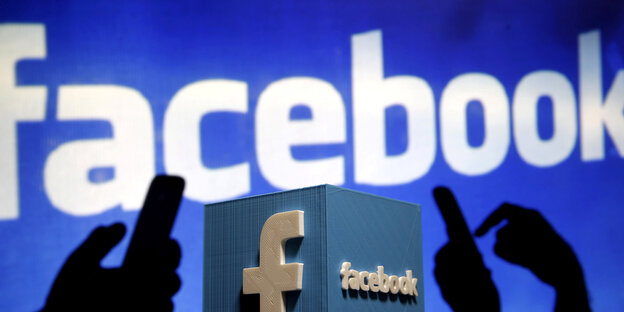 Facebook-Logo und Smartphones als Schatten davor dargestellt Facebook-Logo und Smartphones als Schatten davor dargestellt