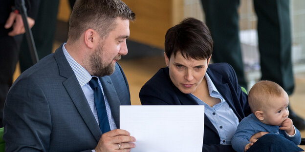 Frauke Petry lehnt sich weit nach rechts um ihrem Sitznachbar in die Notizen gucken zu können, auf dem Schoß hält sie ihr Baby Frauke Petry lehnt sich weit nach rechts um ihrem Sitznachbar in die Notizen gucken zu können, auf dem Schoß hält sie ihr Baby