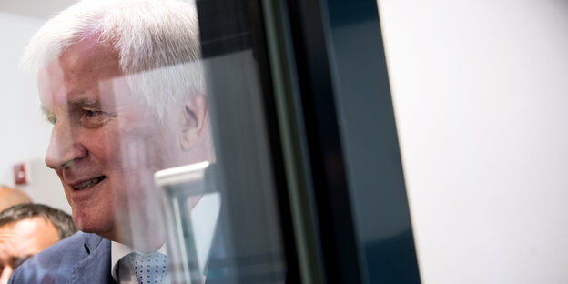 Horst Seehofer steht hinter einer spiegelnden Glaswand Horst Seehofer steht hinter einer spiegelnden Glaswand