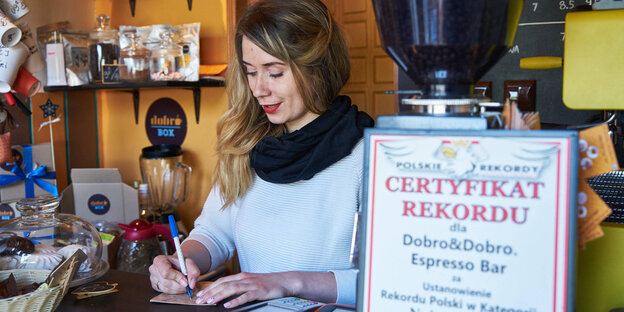 Eine Frau steht hinter einem Café-Tresen Eine Frau steht hinter einem Café-Tresen