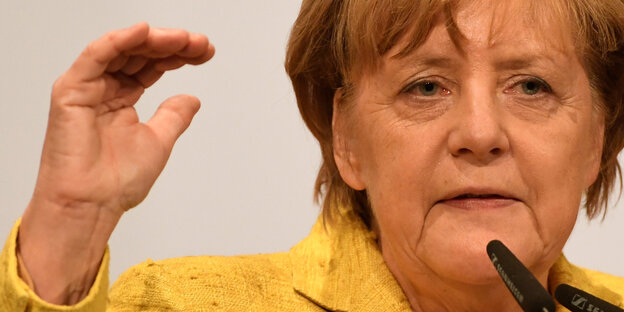 Angela Merkel hält die rechts Hand hoch Angela Merkel hält die rechts Hand hoch