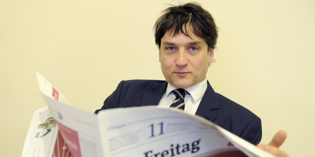 Jakob Augstein hält eine Ausgabe der Wochenzeitung "Der Freitag" aufgeschlagen in den Händen Jakob Augstein hält eine Ausgabe der Wochenzeitung "Der Freitag" aufgeschlagen in den Händen