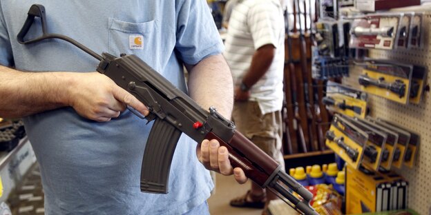 Eine Person hält ein Gewehr in einem Waffenladen Eine Person hält ein Gewehr in einem Waffenladen