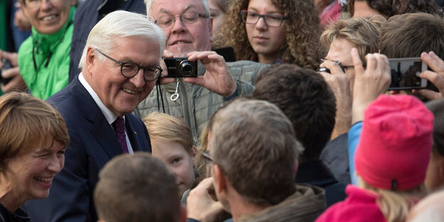 Steinmeier redet mit BürgerInnen. Sie machen Fotos