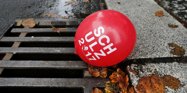 Ein roter Ballon mit der Aufschrift Schulz 2017 liegt auf einem Gulli Ein roter Ballon mit der Aufschrift Schulz 2017 liegt auf einem Gulli