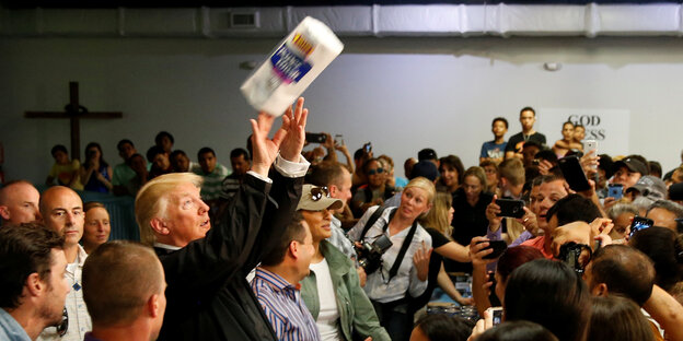 Donald Trump wirft eine Papierrolle in eine Menschenmenge Donald Trump wirft eine Papierrolle in eine Menschenmenge
