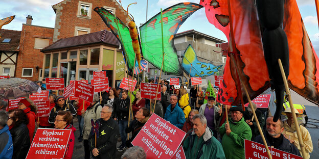 Demonstrant_innen halten Schmetterlingsnachbildungen und Schilder gegen Glyphosat in die Höhe Demonstrant_innen halten Schmetterlingsnachbildungen und Schilder gegen Glyphosat in die Höhe