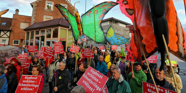 Demonstrant_innen halten Schmetterlingsnachbildungen und Schilder gegen Glyphosat in die Höhe