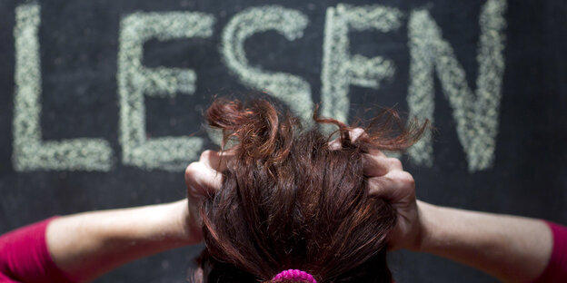 Das Wort „Lesen“ steht an einer Tafel, davor rauft sich eine Person die Haare