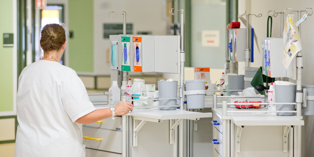 Krankenpflegerin neben zwei Tischen voller Geräte Krankenpflegerin neben zwei Tischen voller Geräte