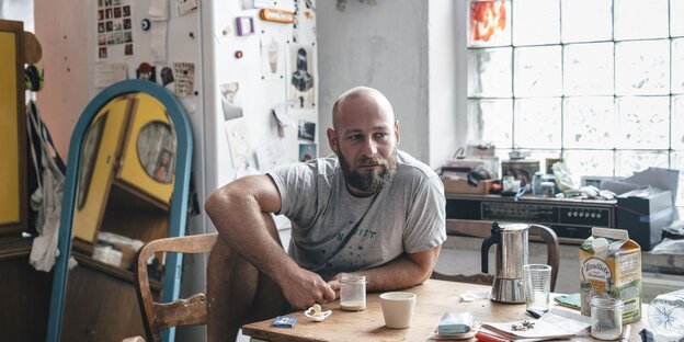 Ein Mann sitzt an seinem Küchentisch und trinkt Kaffee Ein Mann sitzt an seinem Küchentisch und trinkt Kaffee