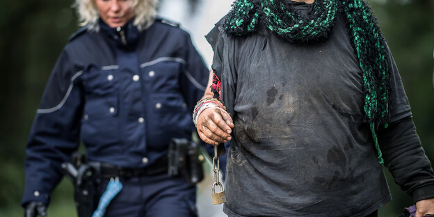 Eine Polizistin führt eine Frau ab. Im Hintergrund ist ein Krankenwagen zu sehen. Eine Polizistin führt eine Frau ab. Im Hintergrund ist ein Krankenwagen zu sehen.