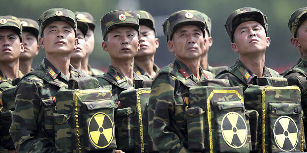 Nordkoreanische Soldaten tragen Taschen vor dem Bauch, die das Zeichen für Radioaktivität ziert Nordkoreanische Soldaten tragen Taschen vor dem Bauch, die das Zeichen für Radioaktivität ziert