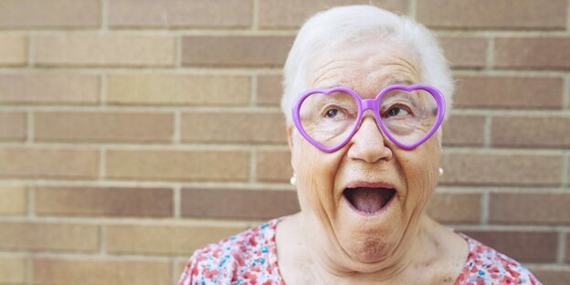 Eine ältere Dame mit einer herzförmigen Brille guckt als hätte sie Spaß Eine ältere Dame mit einer herzförmigen Brille guckt als hätte sie Spaß