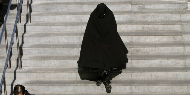 eine Frau in Burka geht eine Treppe hinunter eine Frau in Burka geht eine Treppe hinunter