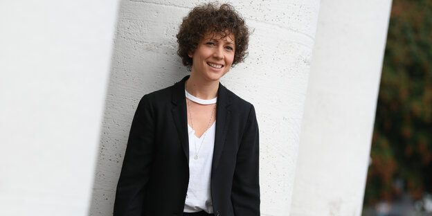 Eine Frau mit Locken vor einer weißen Wand Eine Frau mit Locken vor einer weißen Wand
