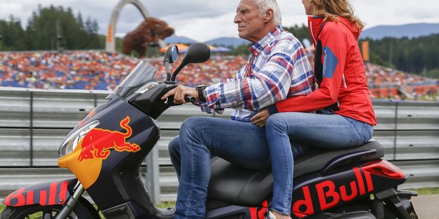 Ein Mann fährt mit einer Frau als Beifahrerin auf einem Red Bull-Motorrad Ein Mann fährt mit einer Frau als Beifahrerin auf einem Red Bull-Motorrad