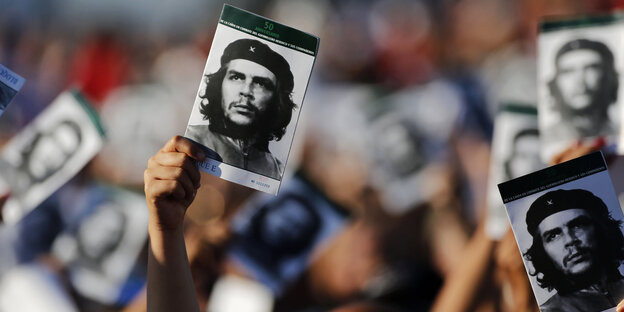 Jemand hält in einer Menschenmenge ein Bild von Che Guevara hoch Jemand hält in einer Menschenmenge ein Bild von Che Guevara hoch