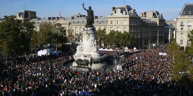 Viele Leute auf einem Platz, in der Mitte ein Denkmal Viele Leute auf einem Platz, in der Mitte ein Denkmal