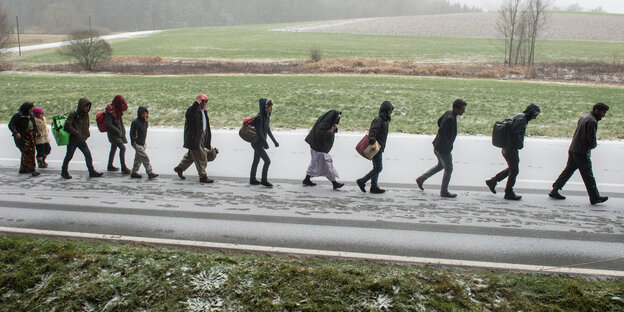 Menschen laufen in einer Reihe auf einer Straße Menschen laufen in einer Reihe auf einer Straße