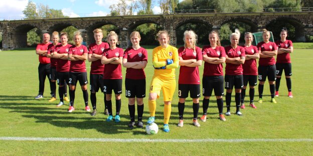 Eine Fußballmannschaft aus Frauen stellt sich pfeilförmig auf. Eine Fußballmannschaft aus Frauen stellt sich pfeilförmig auf.