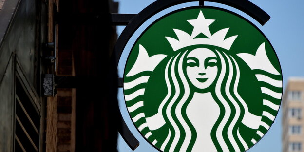 Das Starbuckslogo, besfestigt an der Außenwand eines Ladens Das Starbuckslogo, besfestigt an der Außenwand eines Ladens