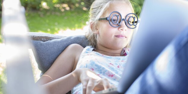 Mädchen mit witziger Brille vor einem Laptop Mädchen mit witziger Brille vor einem Laptop