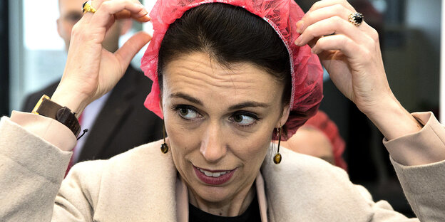 Jacinda Ardern zieht sich eine rosa Haube über den Kopf Jacinda Ardern zieht sich eine rosa Haube über den Kopf