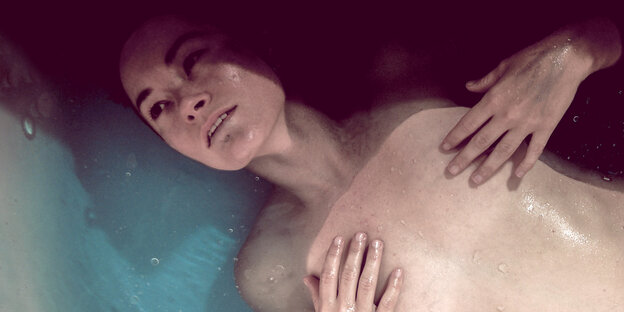 Eine Frau liegt in der Badewanne und berührt ihre Brüste Eine Frau liegt in der Badewanne und berührt ihre Brüste