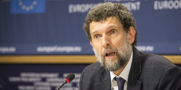 Osman Kavala sitzt am Mikro bei einer Pressekonferenz