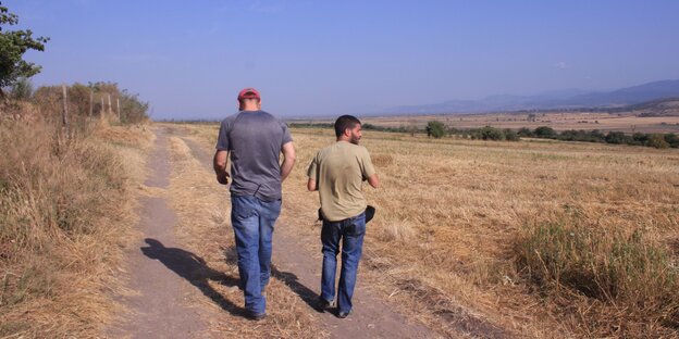 Zwei Menschen gehen auf einem Landweg Zwei Menschen gehen auf einem Landweg