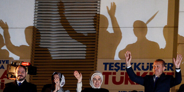 Berat Albayrak, seine Frau und Recep Tayyip Erdogan sowie sein Frau stehen nebeneinander und heben die Arme. Hinter ihnen zeichnen sich ihre Schatten an einer Wand ab Berat Albayrak, seine Frau und Recep Tayyip Erdogan sowie sein Frau stehen nebeneinander und heben die Arme. Hinter ihnen zeichnen sich ihre Schatten an einer Wand ab