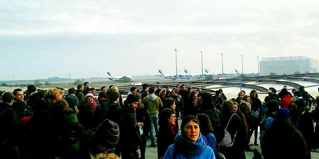 Protestierende stehen am Flughafen in Leipzig/Halle, im Hintergrund Flugzeuge Protestierende stehen am Flughafen in Leipzig/Halle, im Hintergrund Flugzeuge